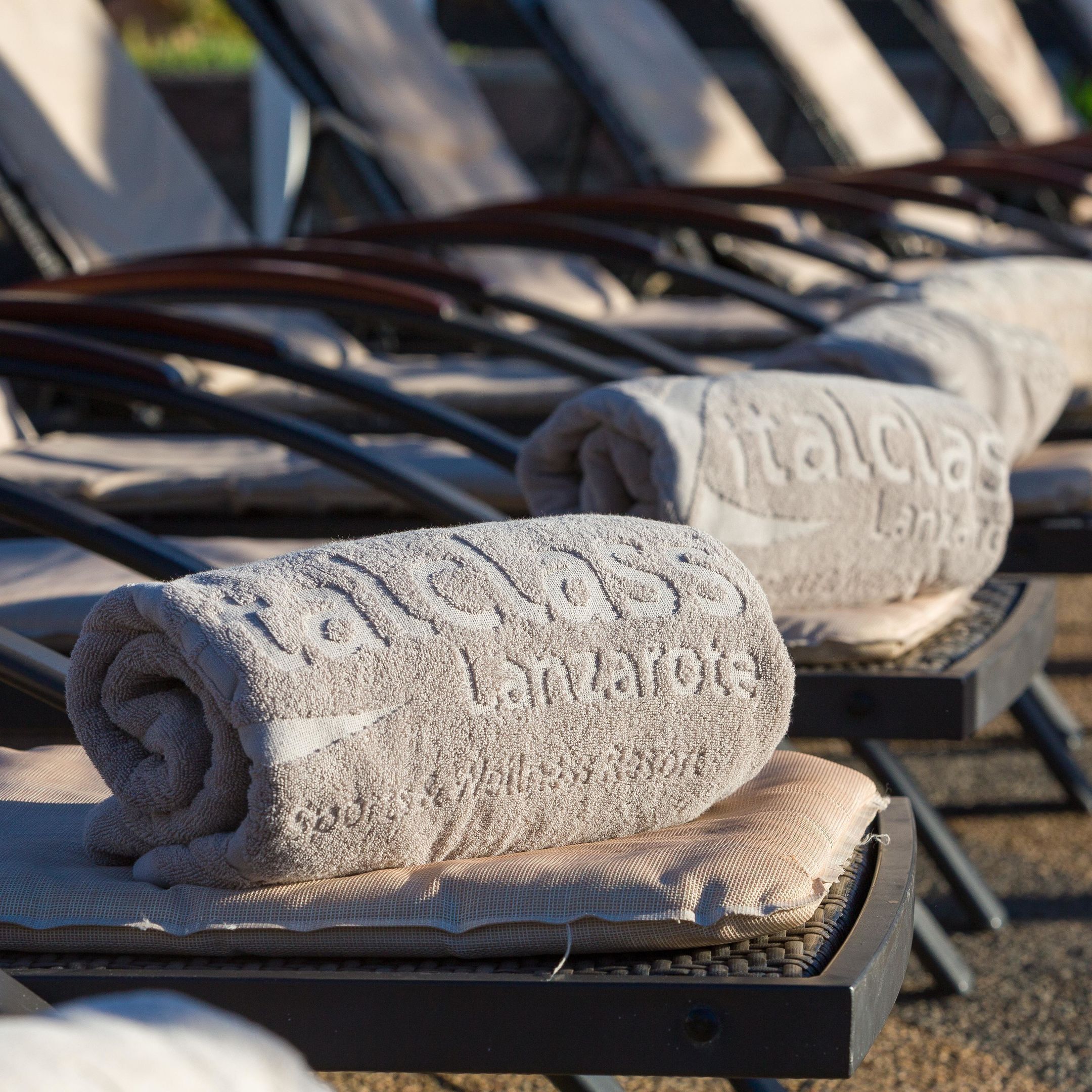 A row of sun loungers with towels rolled up on them.
