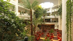 Un atrium à plusieurs niveaux, avec des chaises rouges, des plantes en pot et un escalier central.