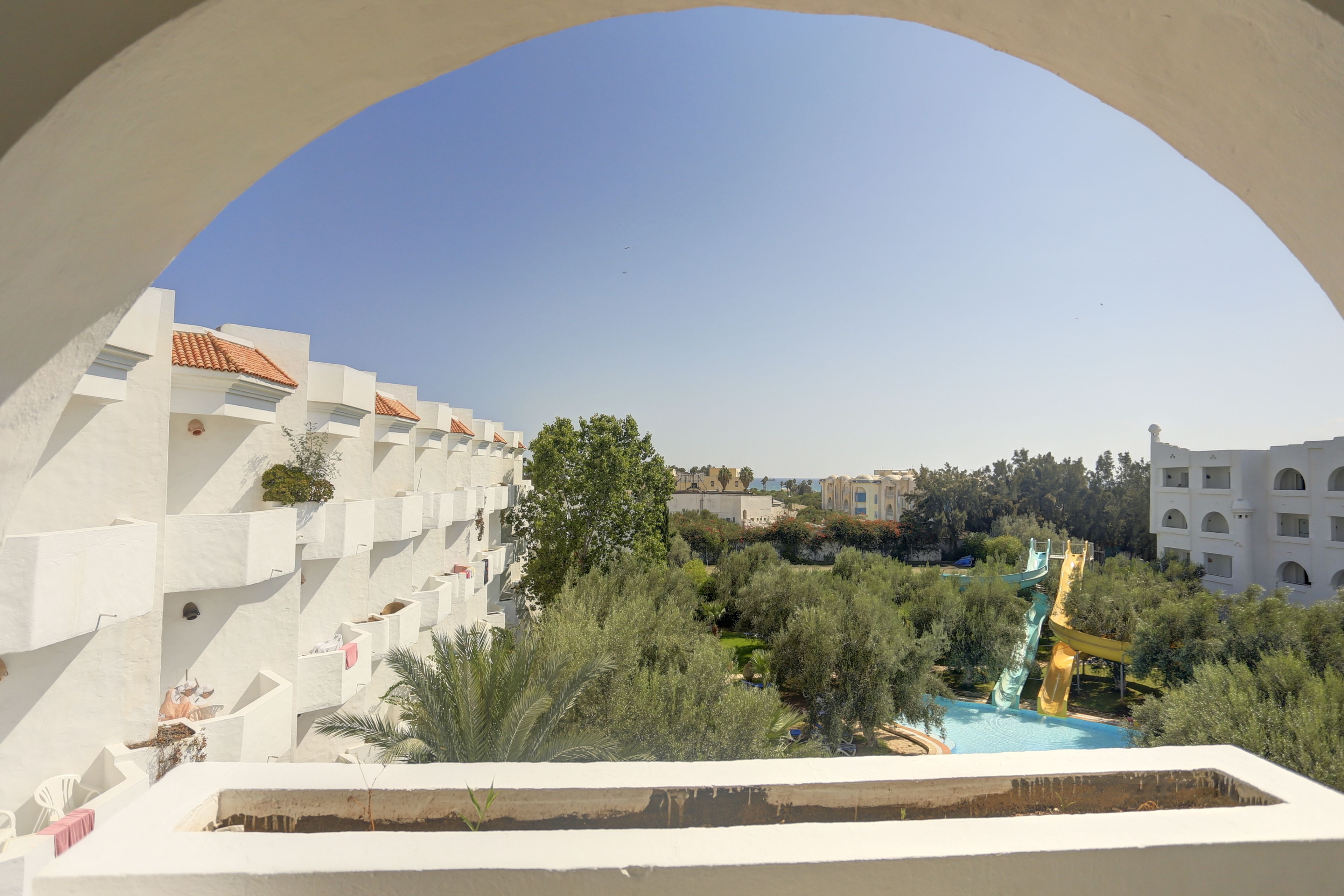 Un resort con edificios blancos, una piscina y un tobogán de agua.