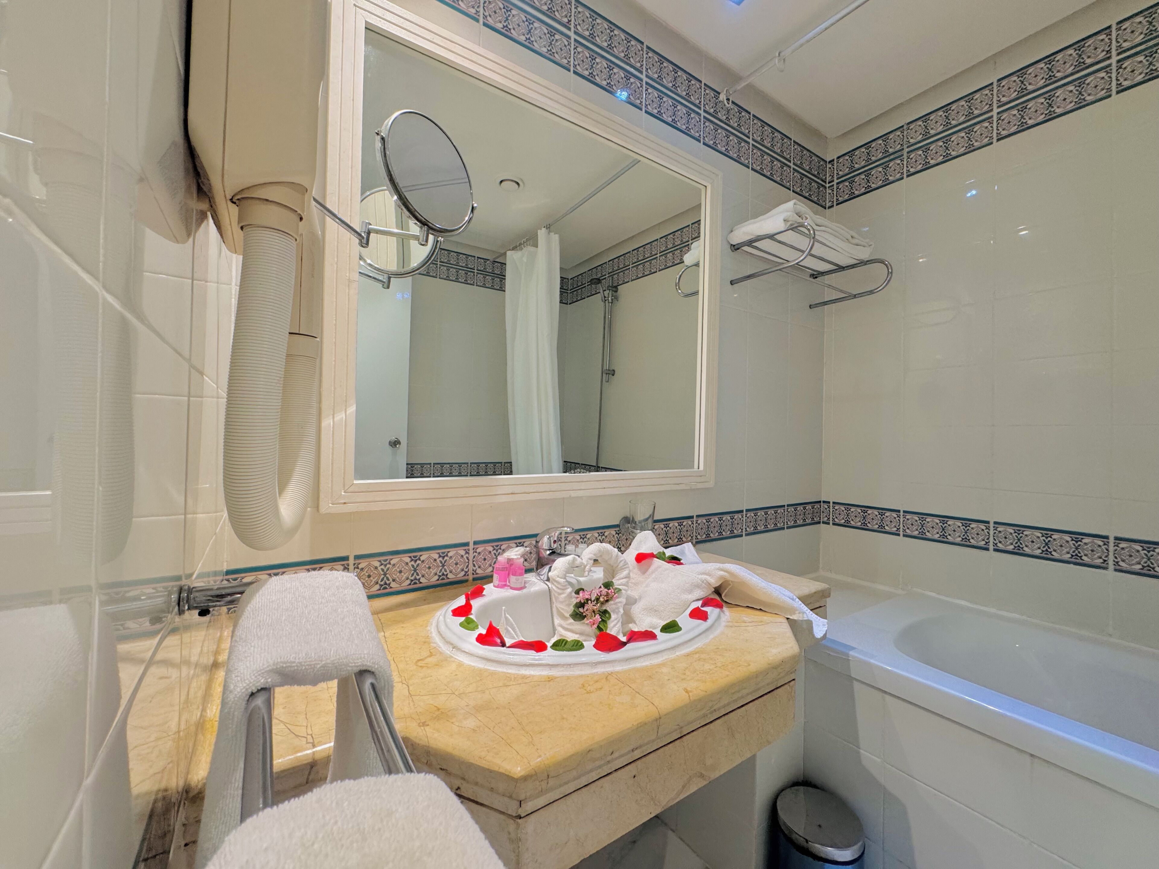 Un baño con bañera, lavamanos con espejo y perchero.