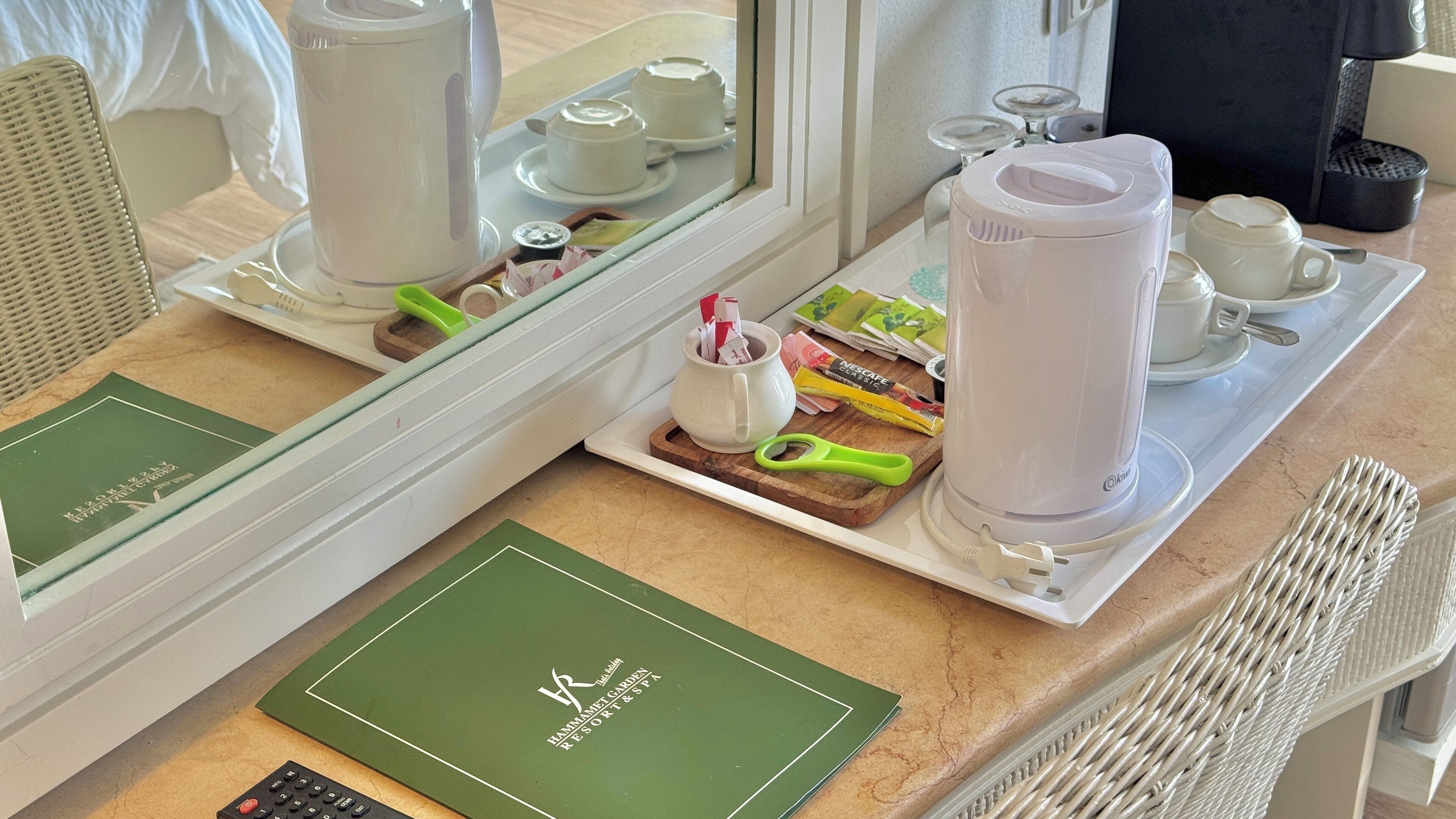 Una camera d'albergo con vassoio per la colazione, una macchina del caffè, una tazza di caffè e un menu verde sul bancone.