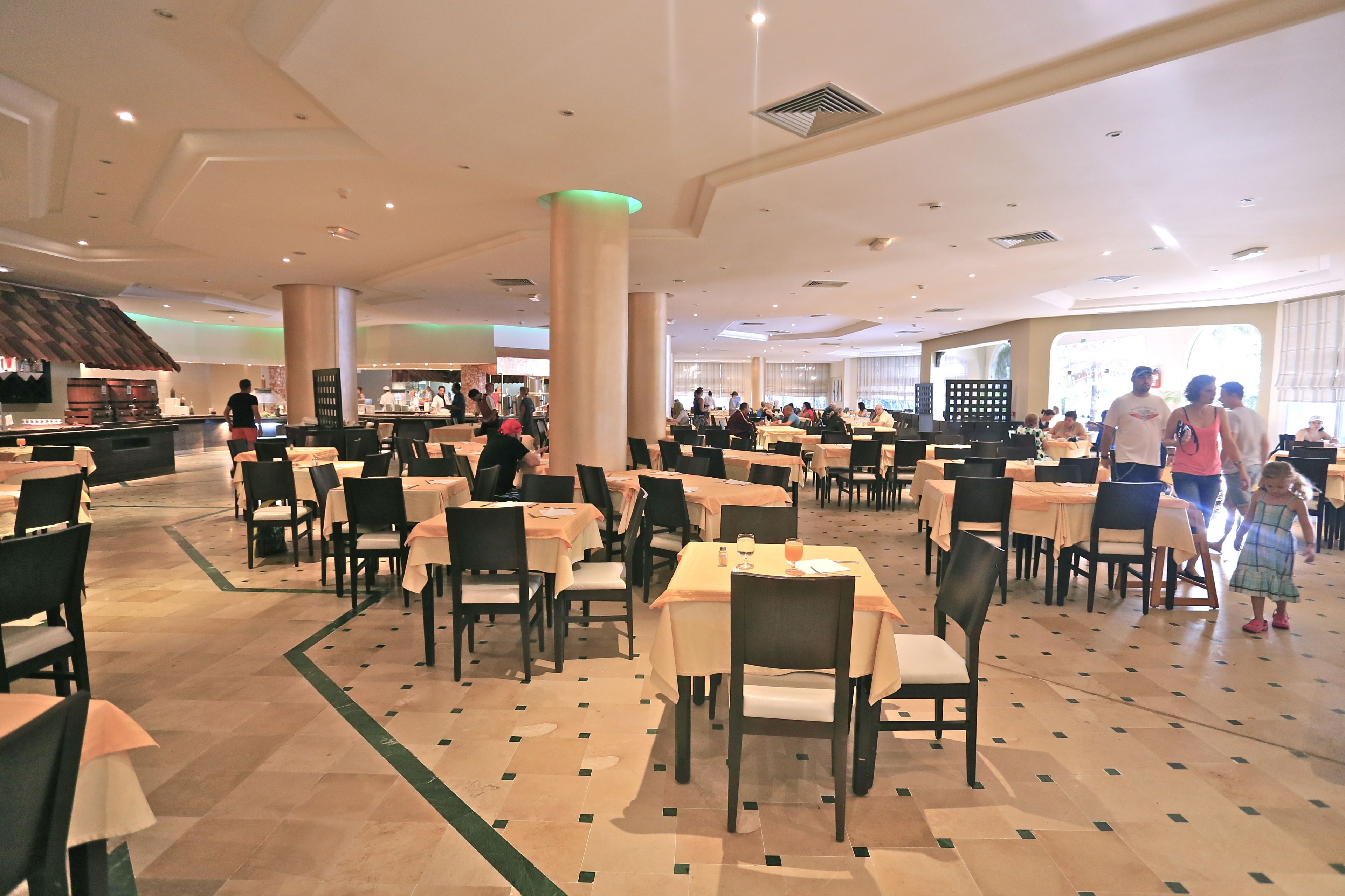 A spacious restaurant with multiple tables and chairs, a bar area, and a view of the outside.