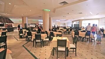A spacious restaurant with multiple tables and chairs, a bar area, and a view of the outside.