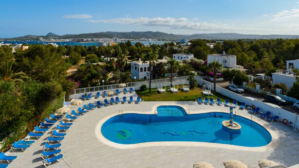 Une piscine d’hôtel avec des chaises longues et une vue sur la mer et les montagnes.
