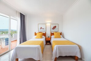 A hotel room with two single beds, a balcony with a view, and a small table with a lamp. - Aparthotel Vibra Monterrey (Sant Josep de sa Talaia)