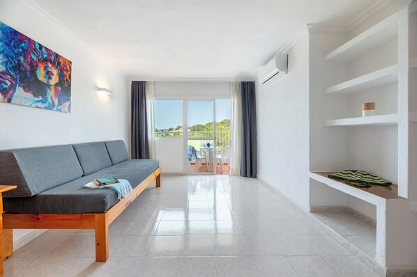 A modern living room with a grey sofa, a wooden coffee table, and a colorful abstract painting on the wall.