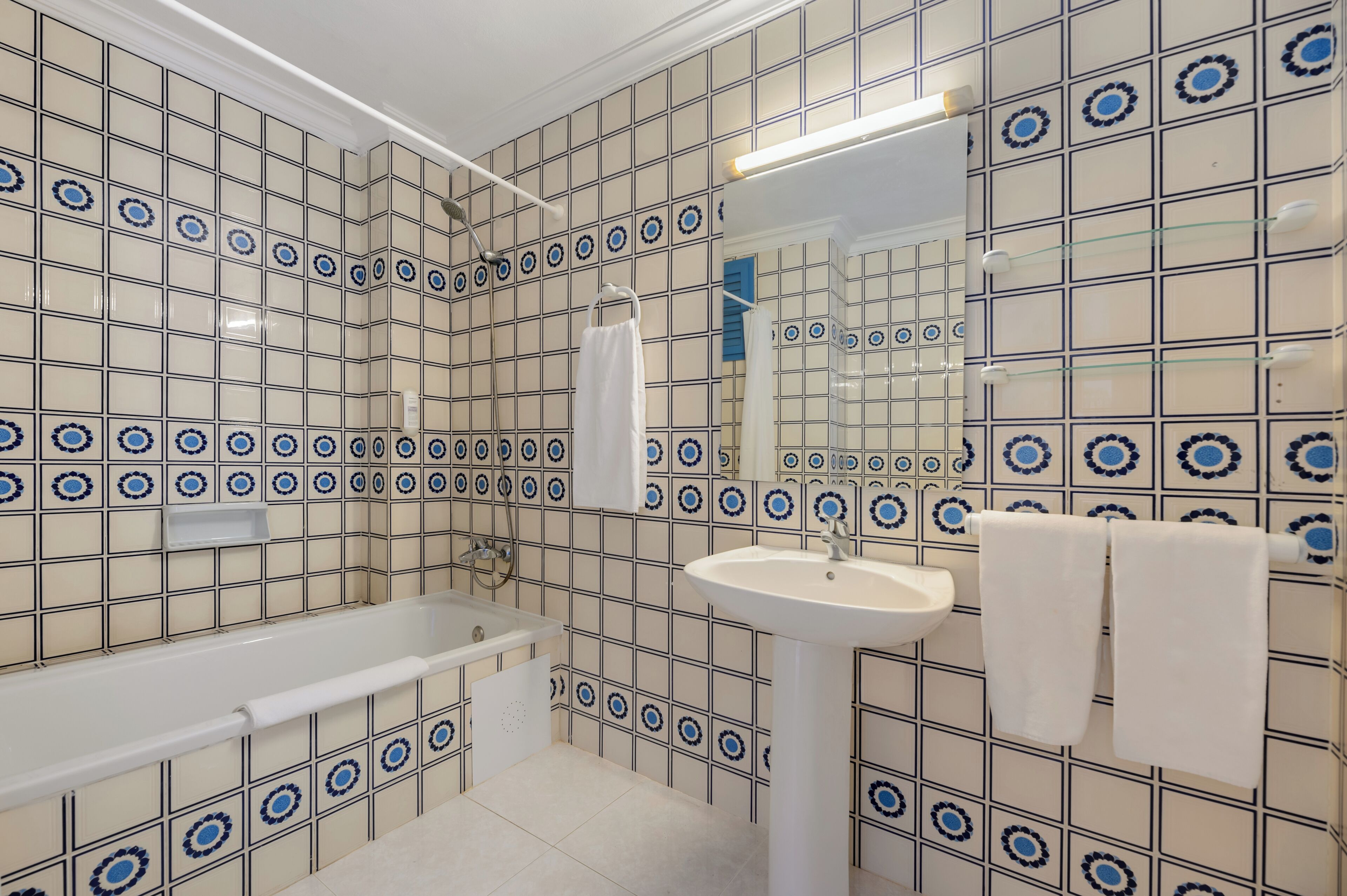 A bathroom with a bathtub, sink, and mirror.