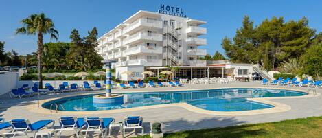 A hotel with a swimming pool, multiple lounge chairs, and a staircase leading to the upper floors.