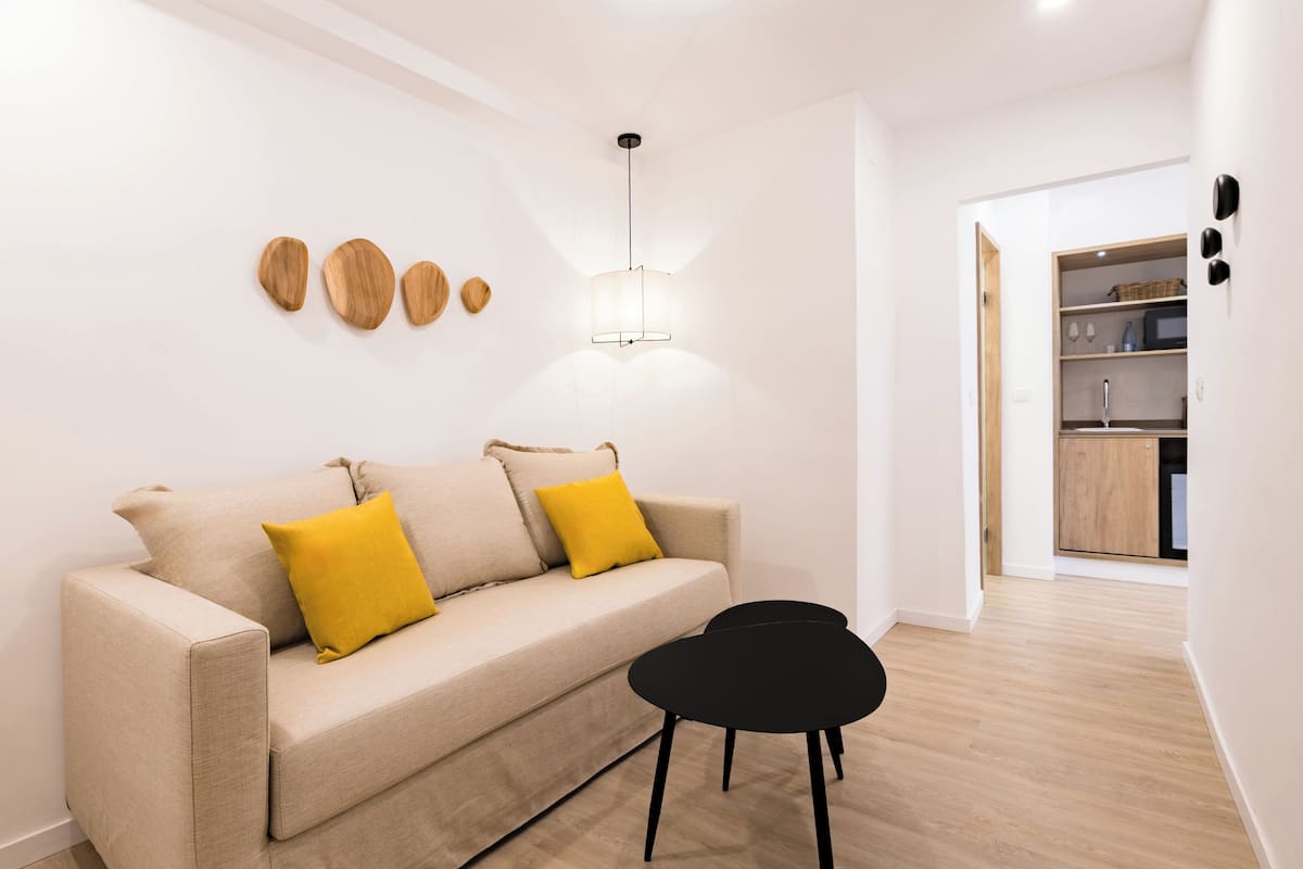 Un salon moderne avec un canapé beige, une table basse noire et un luminaire suspendu.