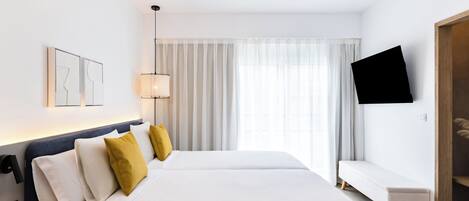 A hotel room with a large bed, bedside tables, a bench, a TV, and a window with curtains.