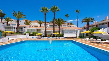 Una piscina al aire libre, sombrillas, sillones reclinables de piscina