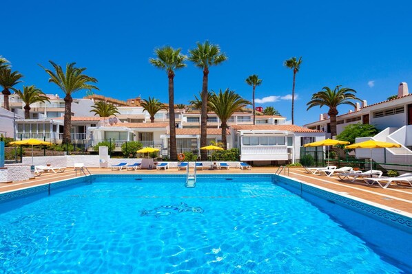 Una piscina al aire libre, sombrillas, tumbonas