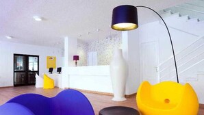 A modern hotel lobby with a reception desk, a staircase, and colorful seating areas. - Paraiso del Sol & Paradero Apartamentos (Adeje)