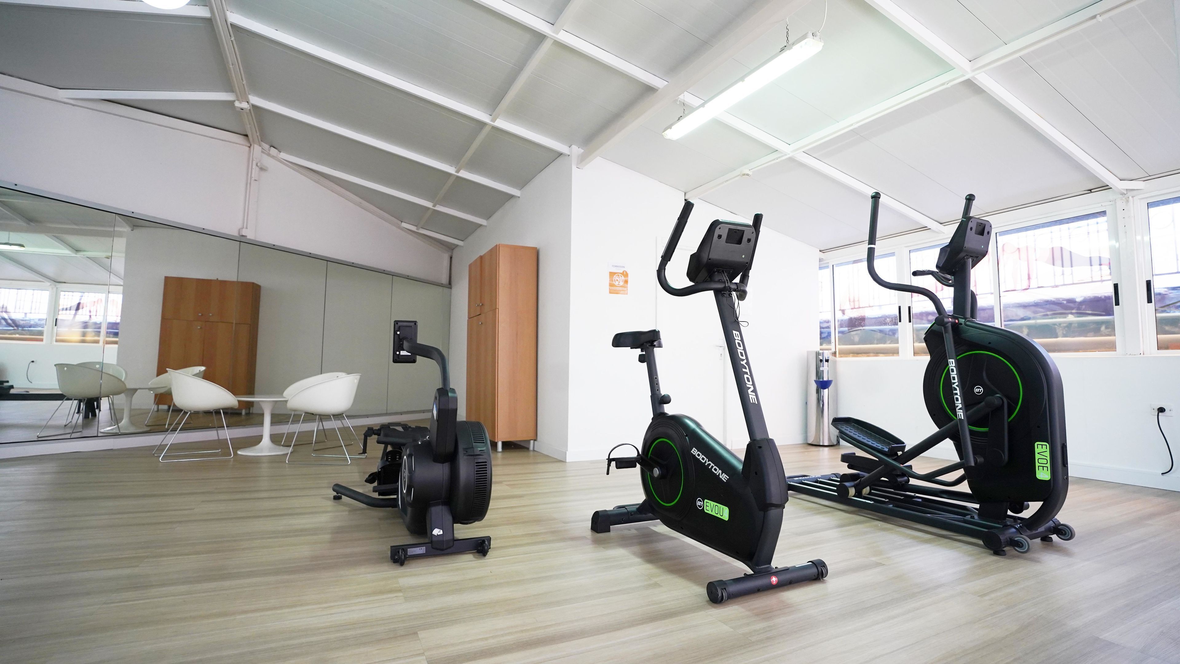Ein Fitnessraum mit Ergometer, Laufband und einer Spiegelwand.