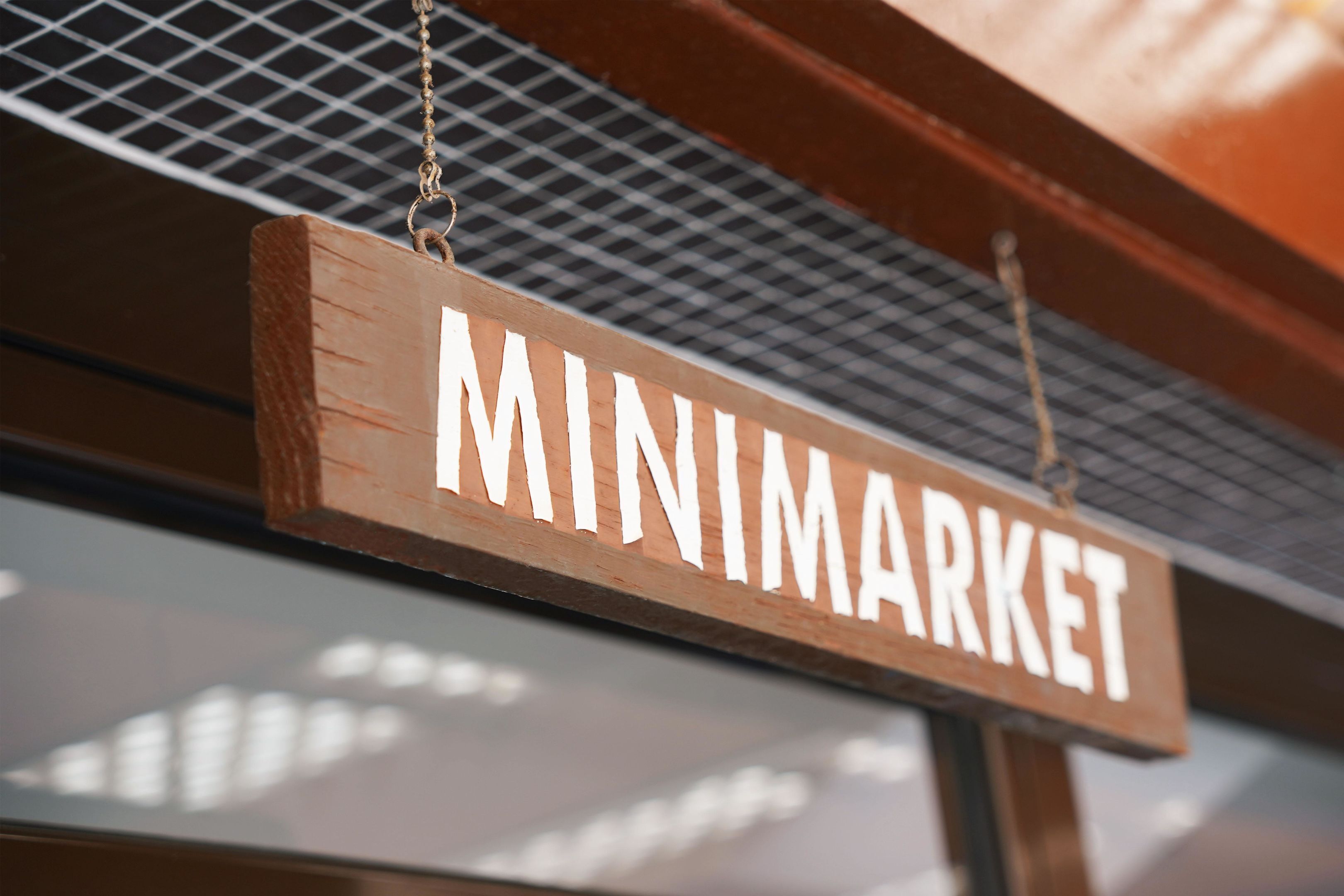 A wooden sign with the word 'MINIMARKET' hanging from a metal structure.