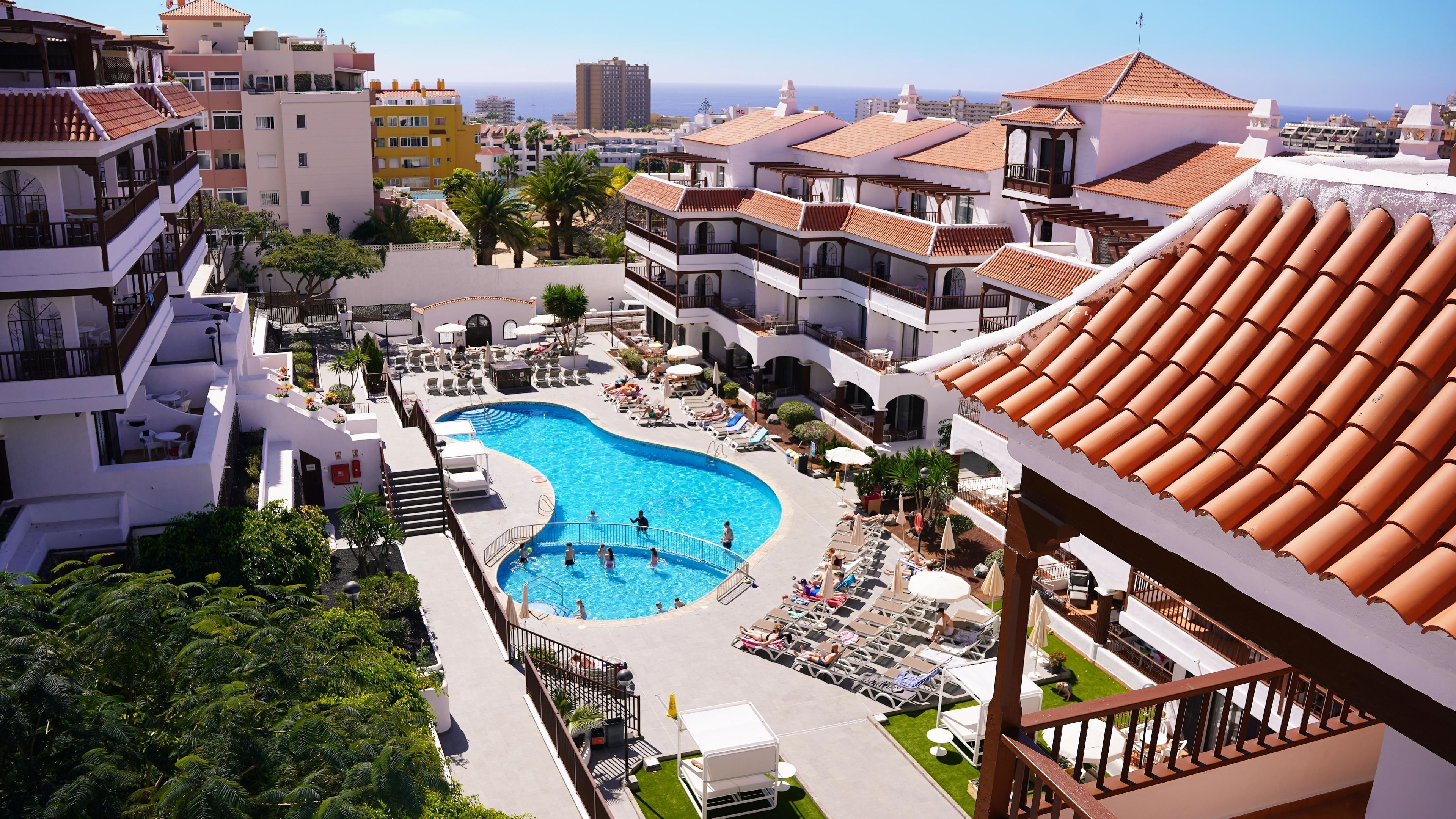 Een resort met een zwembad, terrasgedeeltes en uitzicht op zee.
