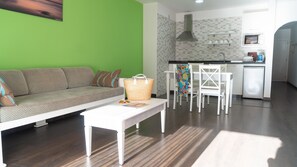 A modern living room with a sofa, a coffee table, and a kitchen area with a microwave and sink. - Coral Los Alisios (Arona)
