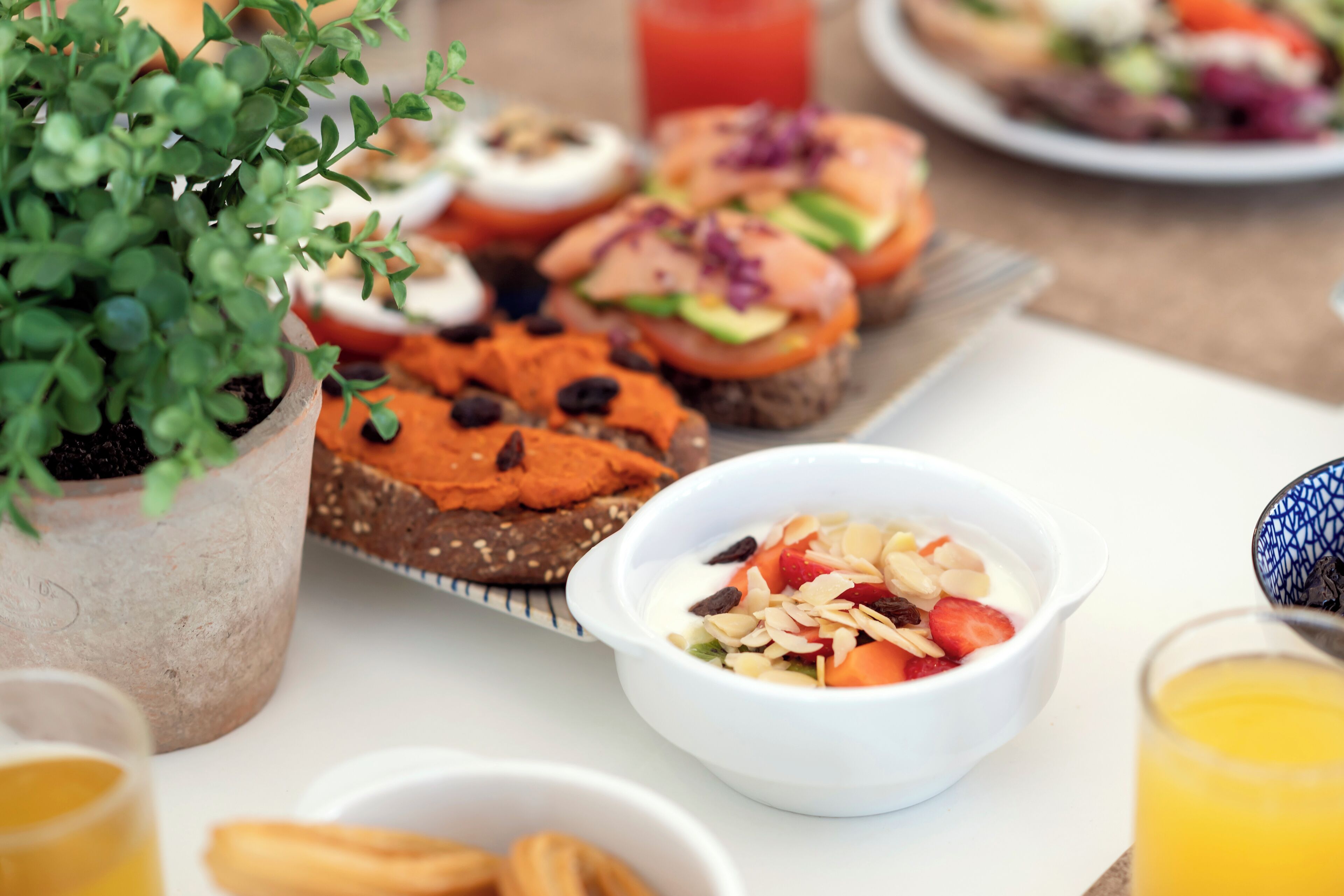 A breakfast setting with various food items, including toast, a bowl of fruit salad, and a glass of orange juice.