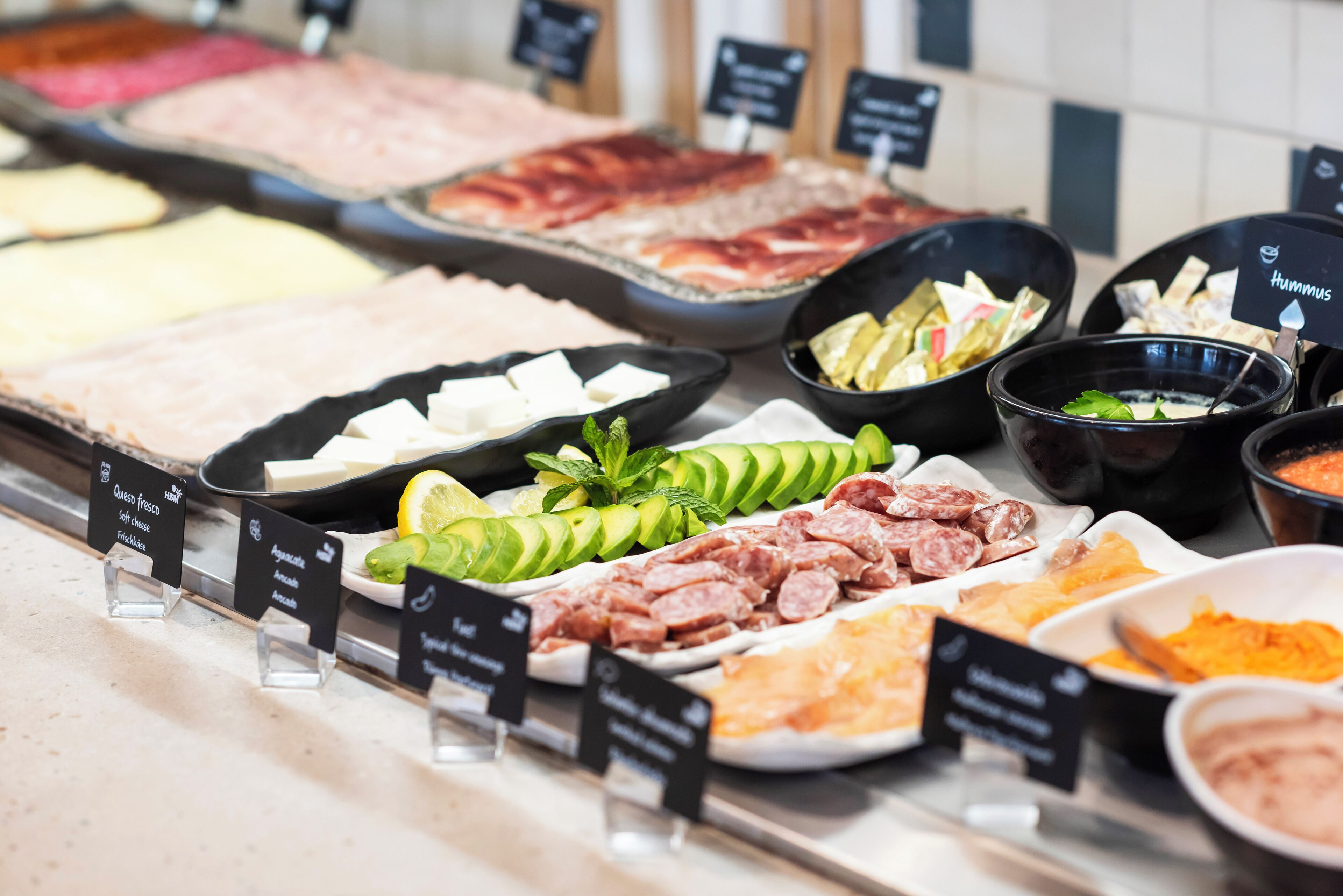 A buffet with various food items including meats, cheeses, and vegetables.