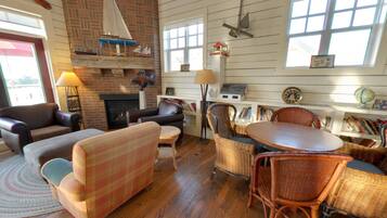 A cozy living room with a fireplace, wooden floors, and a bookshelf filled with books.