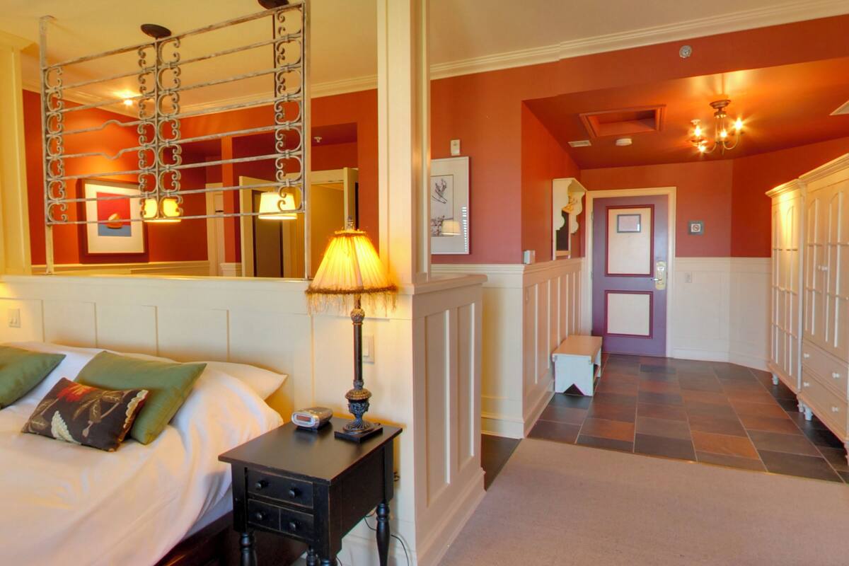 Habitación de hotel con cama, mesita de noche, lámpara y armario.