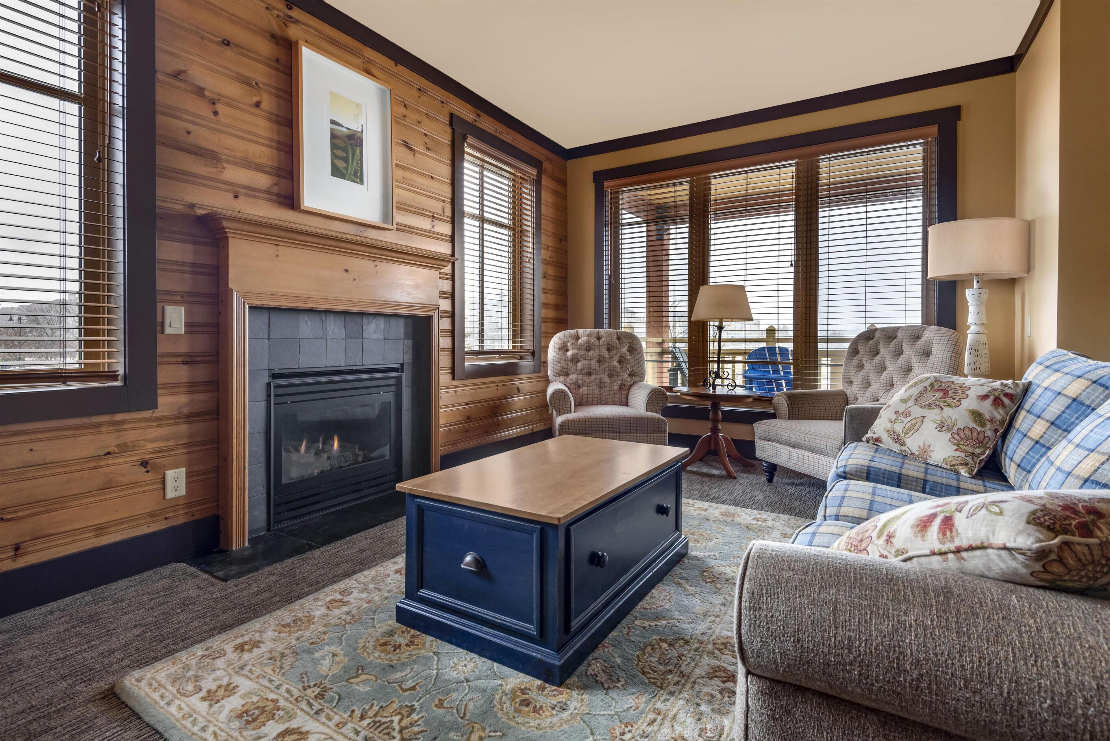 A cozy living room with a fireplace, two armchairs, a sofa, and a coffee table.