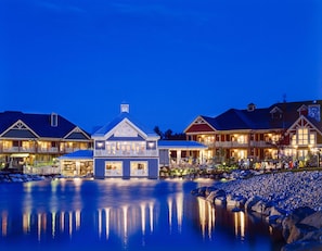 A waterfront hotel with multiple buildings, a large central structure, and a calm reflective water body.