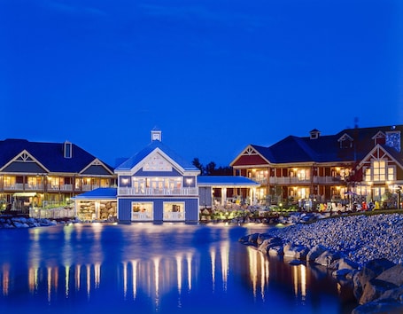 A waterfront hotel with multiple buildings, a large central structure, and a calm reflective water body.