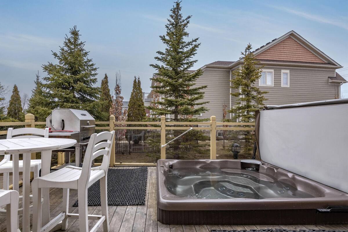 Un patio con jacuzzi, mobiliario exterior y una parrilla.
