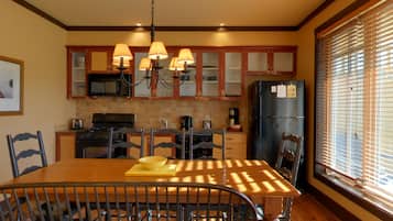 A kitchen with wooden cabinets, a black refrigerator, a stove, and a dining table with chairs.