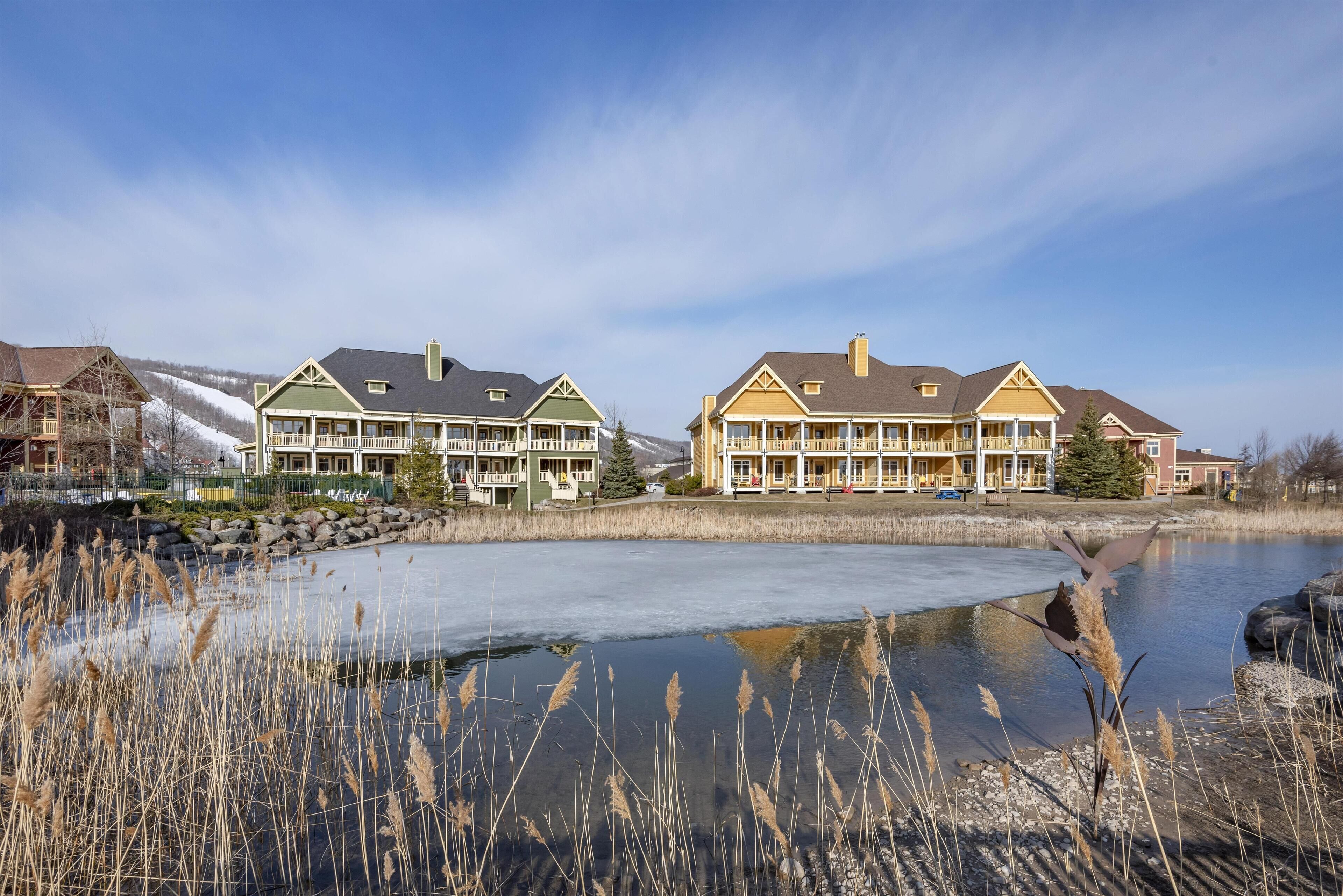 Et hotel ved søen med to hovedbygninger, et overdækket udendørsområde og en frossen sø.