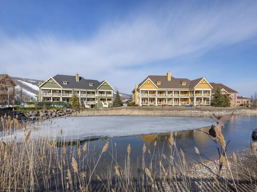 Et hotel ved søen med to hovedbygninger, et overdækket udendørsområde og en frossen sø.
