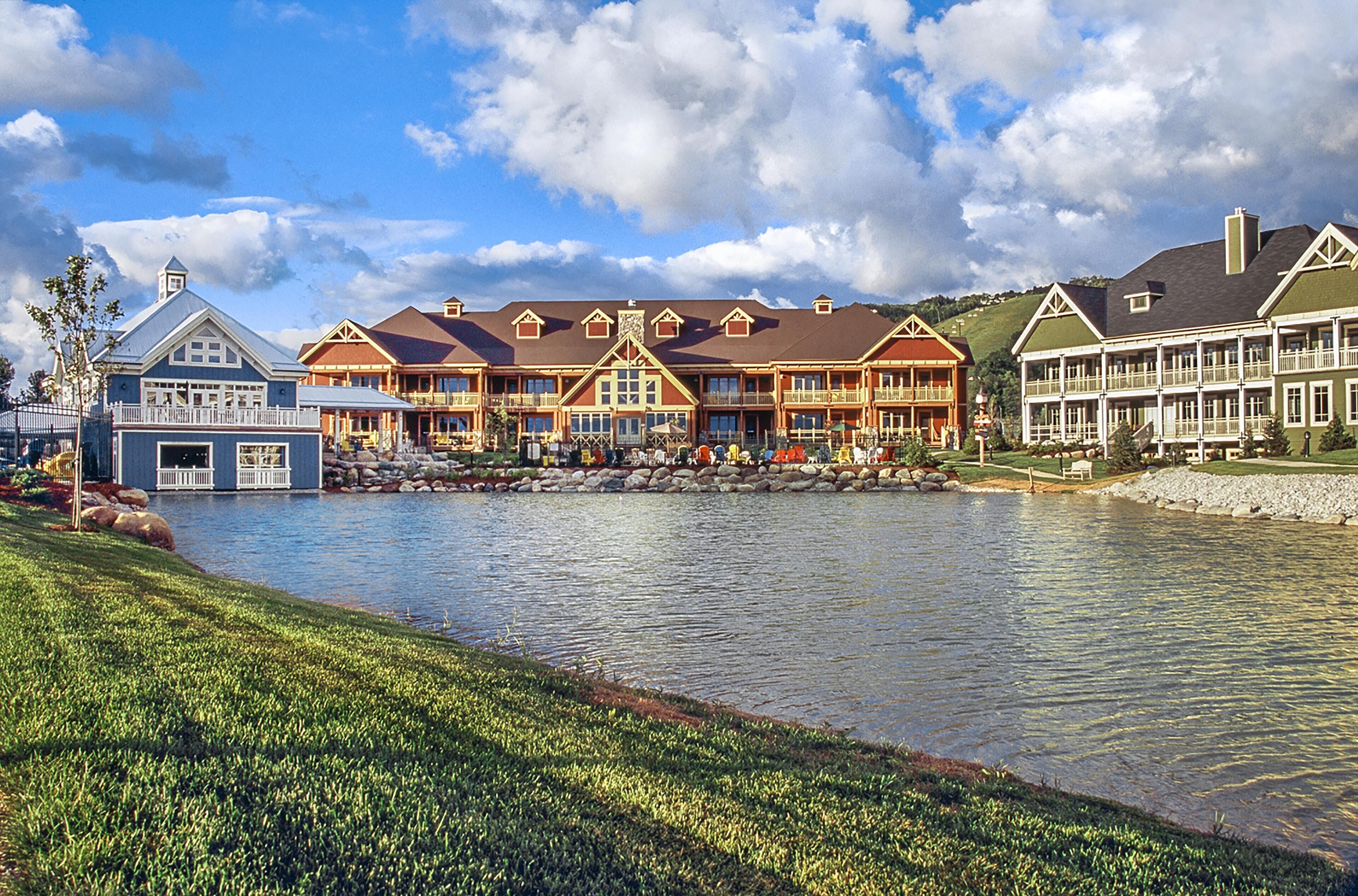 Een groot resort met meerdere gebouwen, een meer en een verzorgd gazon.