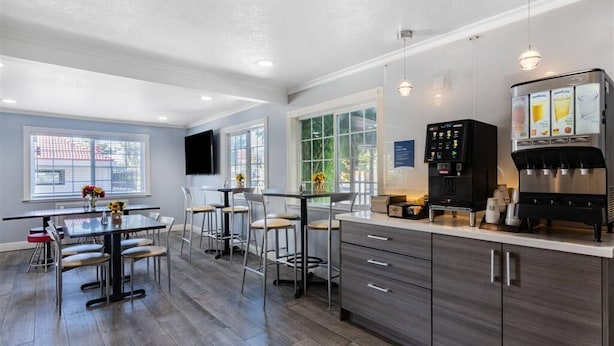 Una cocina moderna con cafetera, taburetes de bar y un comedor con mesa y sillas.