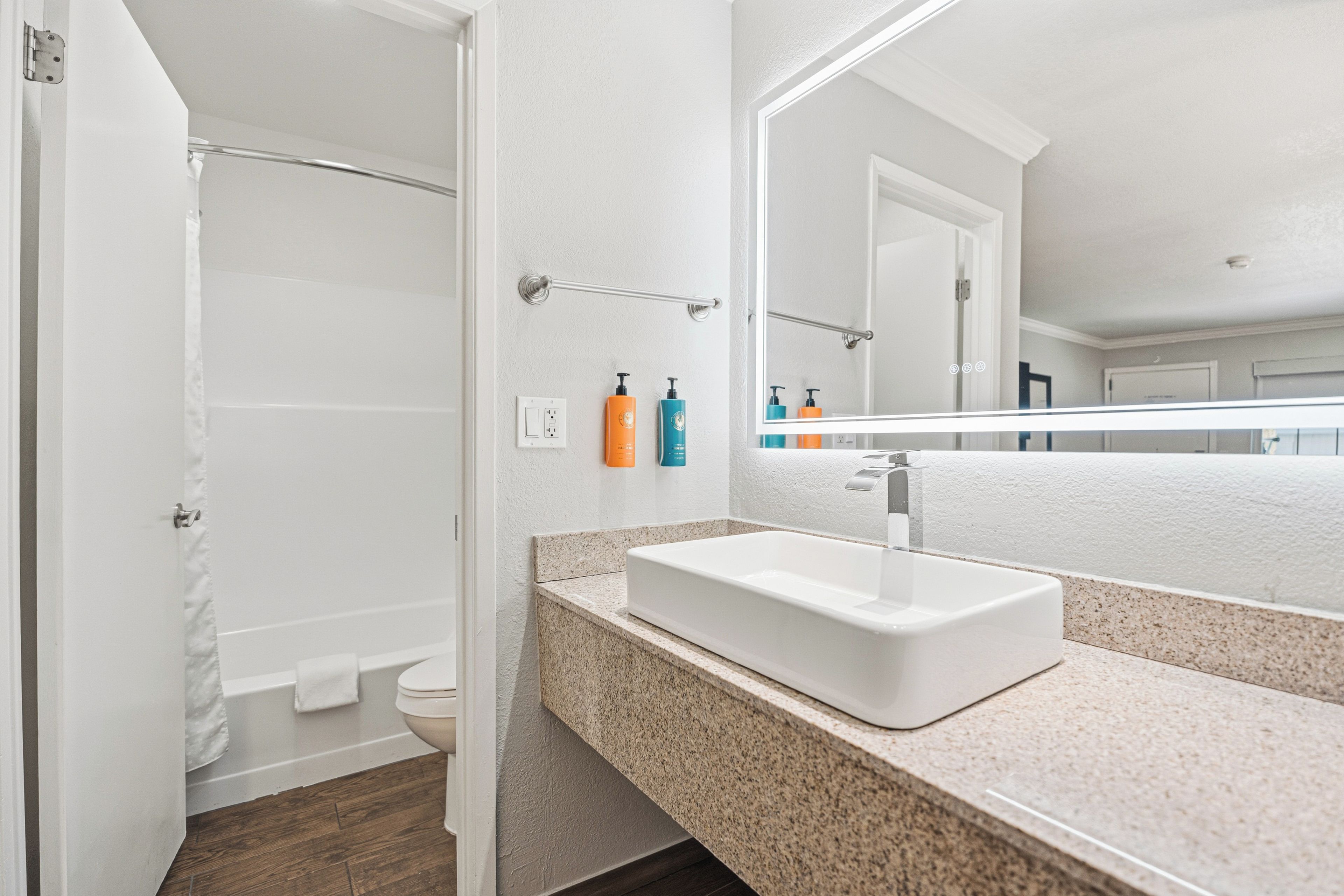 A bathroom with a white sink, a mirror, and toiletries on the wall.