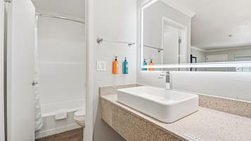 A bathroom with a white sink, a mirror, and toiletries on the wall.