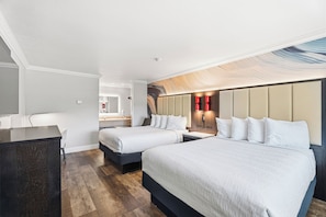 Habitación de hotel con dos camas, un escritorio, una silla, baño y vistas a la ciudad.