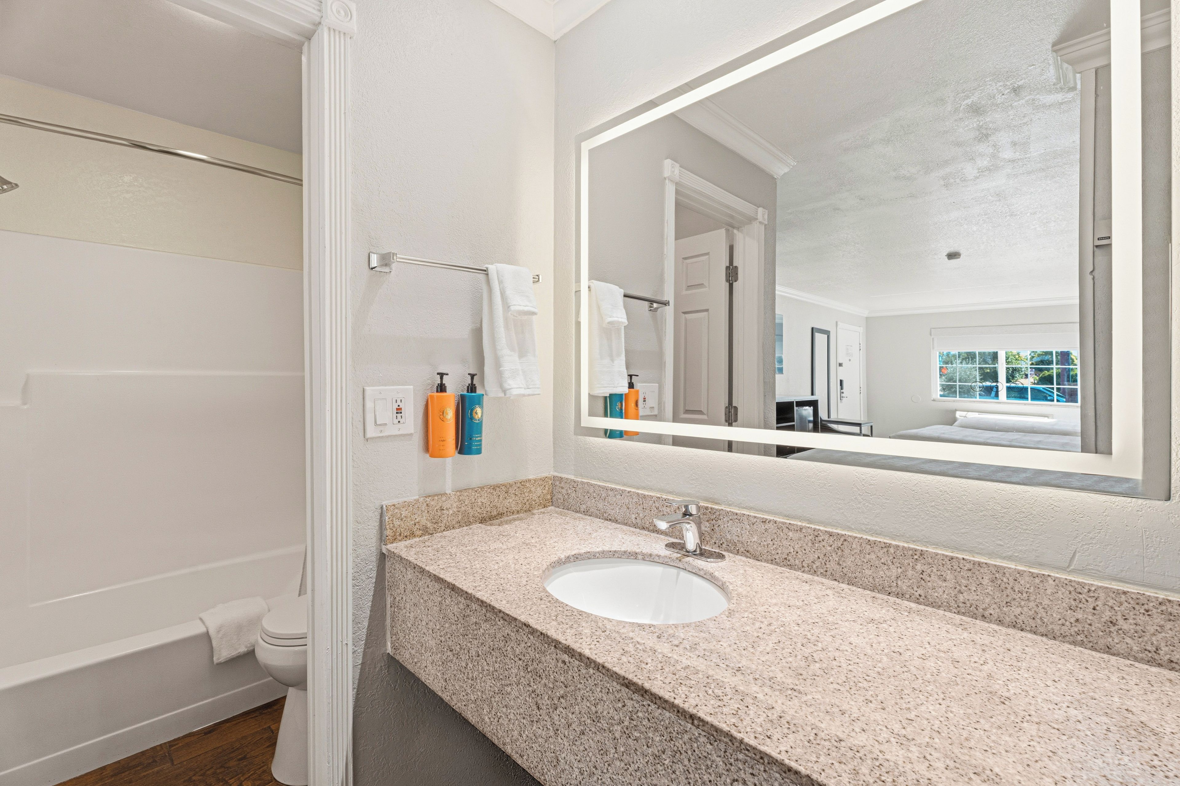 A bathroom with a granite countertop, a white sink, and a large mirror.