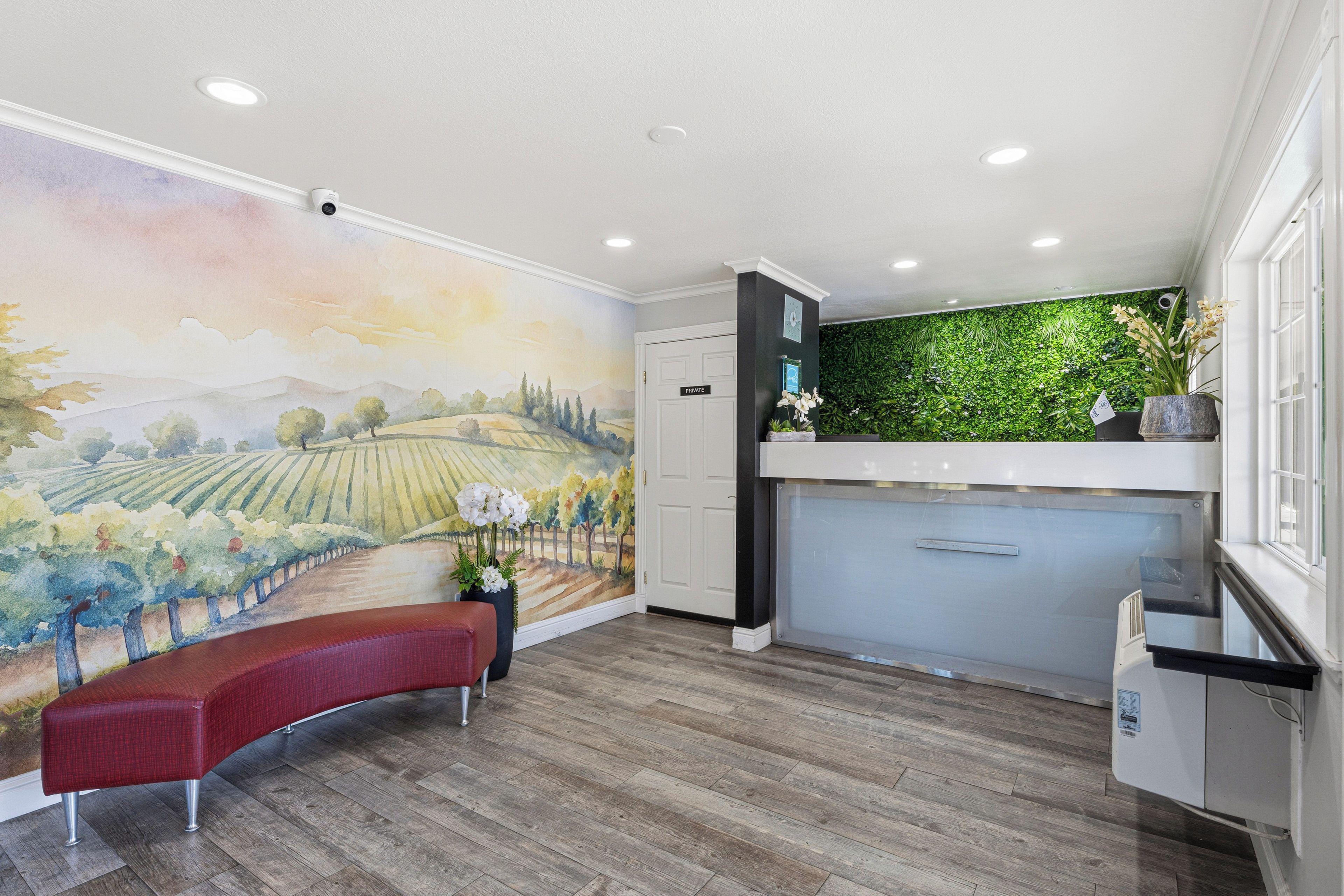 A reception area with a mural, a bench, a green wall, and a wooden floor.