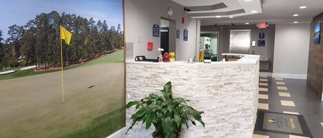 A reception area with a golf course view, a reception desk, and a potted plant.