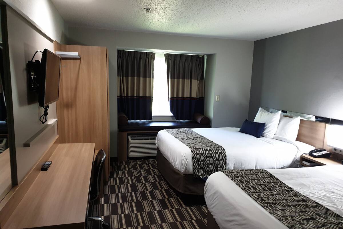 A hotel room with two beds, a desk, a TV, and a phone.