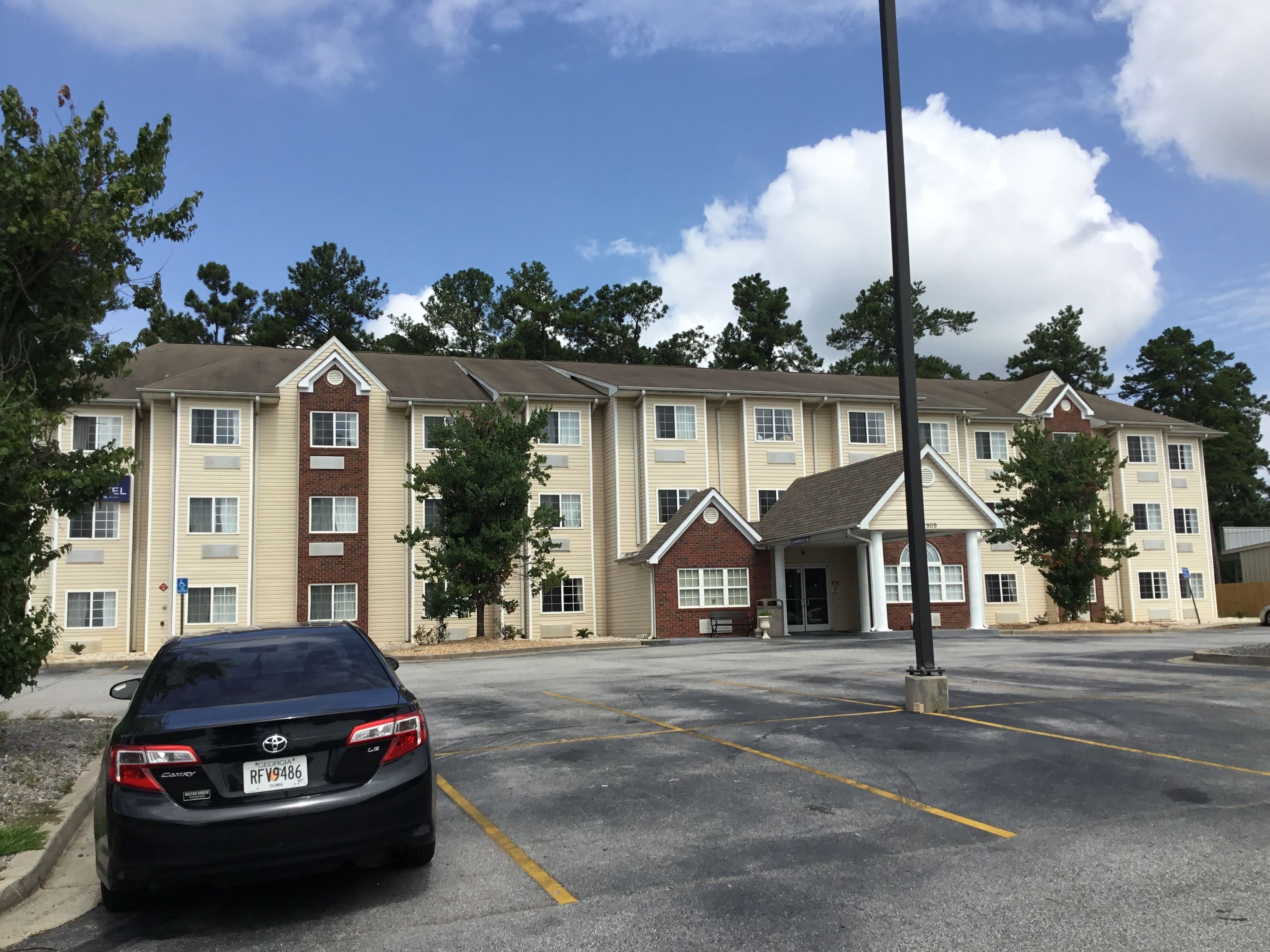 A multi-story hotel with a parking lot in front.