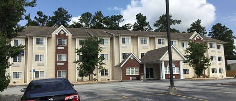 A multi-story hotel with a parking lot in front.