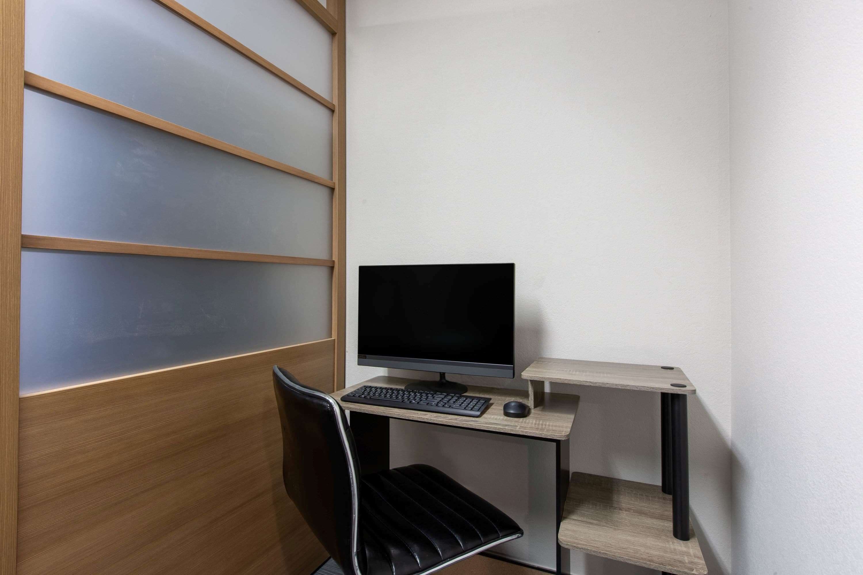 A small, modern office space with a desk, computer, and chair.