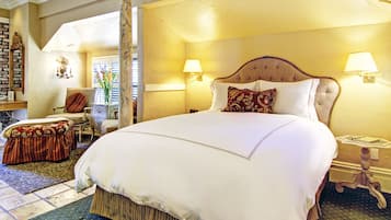 A large bed with a wooden headboard, two bedside lamps, and a floral arrangement on a nightstand.