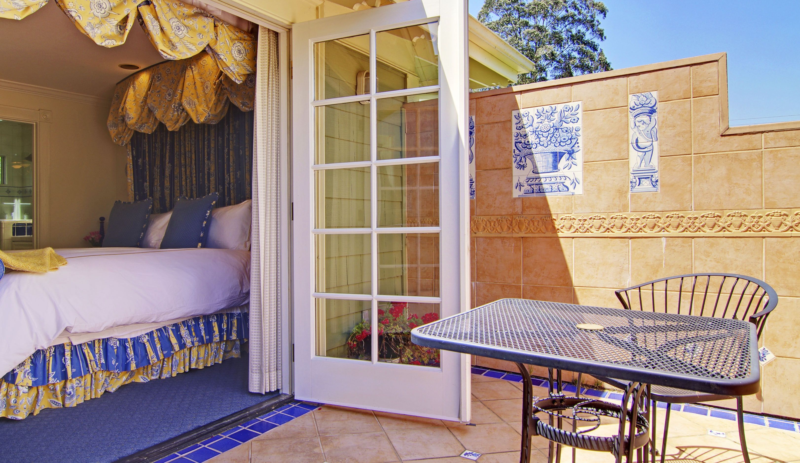 A bedroom with a bed, a sliding glass door, a patio table, and chairs.
