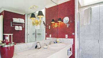 A modern bathroom with a large mirror, a white sink, and a red accent wall.