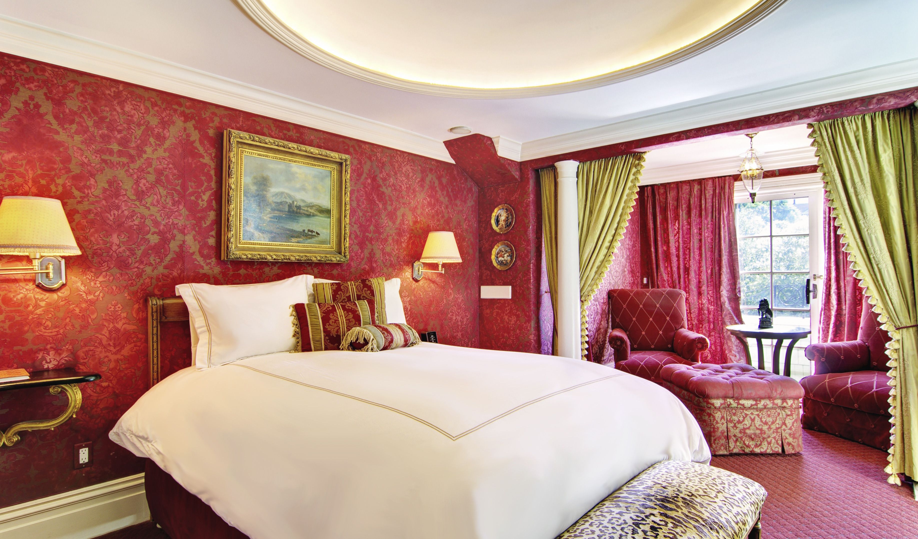 A hotel room with a large bed, a chair, a table, and a painting on the wall.