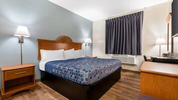 A hotel room with a bed, bedside tables, a desk, and a window with curtains.