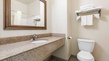 A bathroom with a granite countertop sink, a white toilet, a wall-mounted towel rack, and a mirror with a decorative frame.